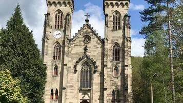 A historic church with twin towers, a central arched window, and a clock.