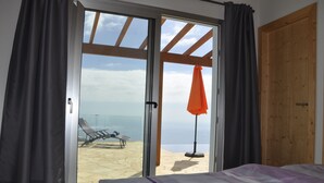 Ein Schlafzimmer mit einer großen Schiebeglastür, die auf einen Balkon mit Blick auf den Strand führt.