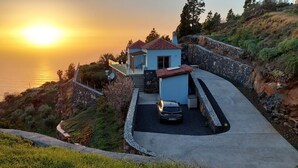 Ein Küstenanwesen mit einer Auffahrt, die zu einem Haus mit einer Steinmauer und einer kleinen angebauten Garage führt.