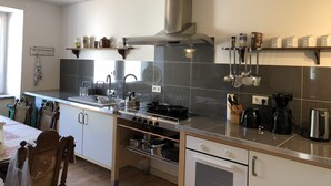 Een moderne keuken met een centraal eiland, roestvrijstalen apparatuur en diverse keukengerei en pannen.