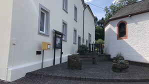 Een smalle straat met cobblestones, witte gebouwen, een brievenbus en een kleine tuin met potplanten.