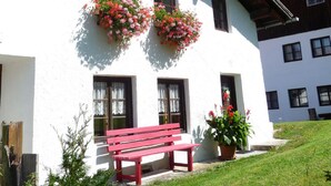 A white building with wooden beams, a red bench, and flower boxes on the windows. - Quaint farmhouse with comfort and a typical atmosphere (Biberwier)