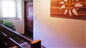 A hallway with a wooden door, a bench, and a wall-mounted artwork. - Quaint farmhouse with comfort and a typical atmosphere (Biberwier)