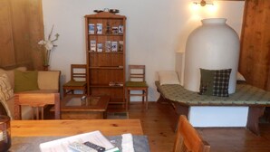 A cozy living room with a wooden bookshelf, a large white urn, and a bench with a patterned cushion. - Quaint farmhouse with comfort and a typical atmosphere (Biberwier)