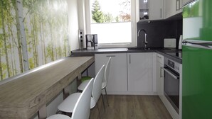 Eine moderne Küche mit weißen Schränken, einem eingebauten Ofen, einem grünen Kühlschrank und einem Fenster, das für natürliches Licht sorgt.