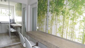 Eine moderne Küche mit einer Holztischplatte, weißen Stühlen und einer Wandmalerei von Bäumen.