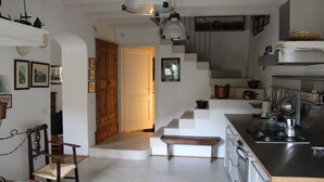 A kitchen with a central island, a staircase leading to a loft, and a dining area with a bench. - Lake Garda: Idyllic villa in quiet village center with olive and palm trees garden (Nago-torbole)