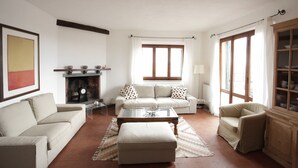 A living room with a fireplace, two sofas, a coffee table, and a cabinet. - Nido delle Campane - Romantic apartment with 2 terraces with panoramic-sea views (Castiglione della Pescaia)