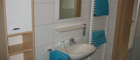 A bathroom with a white sink, a mirror, a towel rack, and a wooden cabinet.