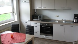 Una cocina compacta con armarios blancos, un microondas, una estufa y un lavamanos.