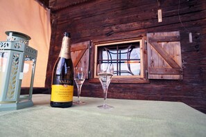 A bottle of Valdobbiadene Prosecco and two wine glasses on a table in a rustic wooden room with a window. - comfortable blockhouse for 2 persons with garden, lake nearby (Krumpendorf)