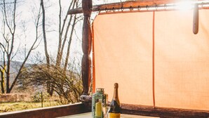 Una mesa de madera con mantel verde, una botella de vino y una vela encima.