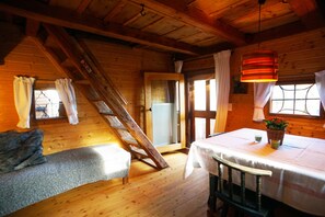 A wooden cabin interior with a loft bed, a dining table with a basket of flowers, and a wooden staircase. - comfortable blockhouse for 2 persons with garden, lake nearby (Krumpendorf)