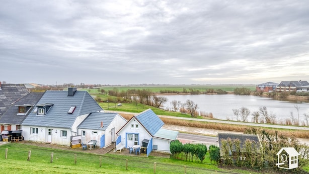 Un barrio residencial con casas, un río y un campo distante.