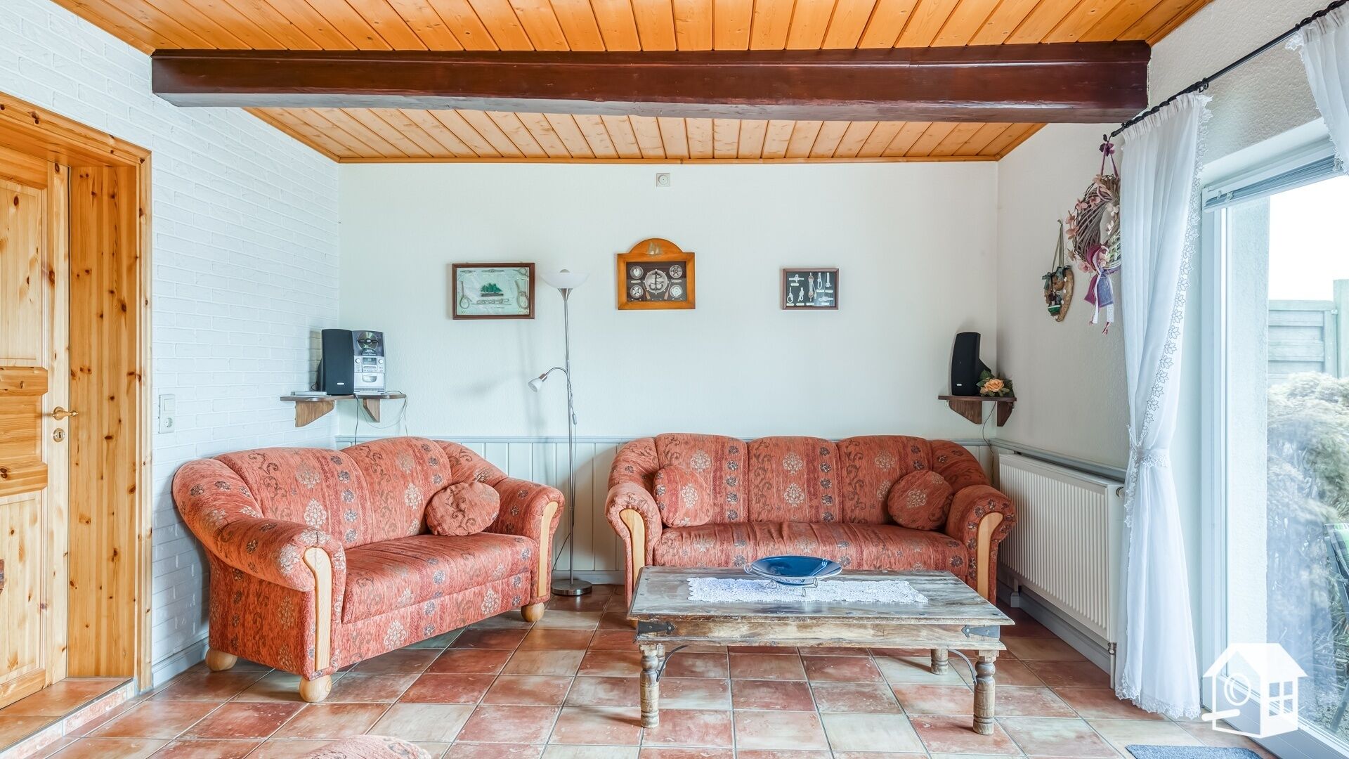 A living room with two patterned sofas, a coffee table, and a wooden ceiling.