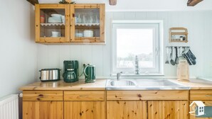 Una cocina con armarios de madera, cafetera, hervidor y tostadora.