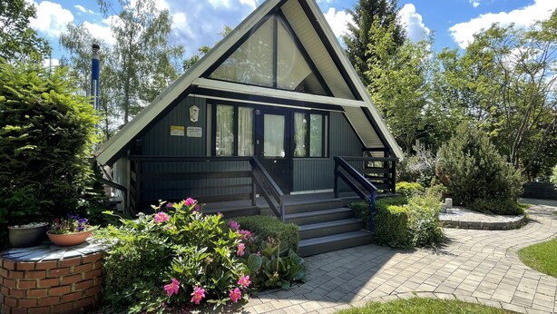 A small, modern cabin-style building with a sloped roof and a staircase leading to the entrance. - With sauna and fireplace (Rheinboellen)