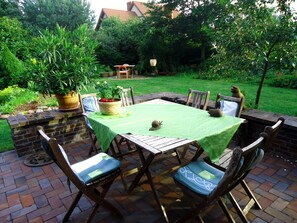 Un patio al aire libre con una mesa dispuesta para cuatro personas, rodeado de muros de ladrillo y sillas de madera.
