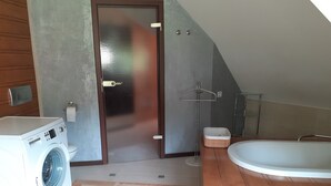 Ein modernes Badezimmer mit Waschmaschine, freistehender Badewanne und Handtuchhalter.