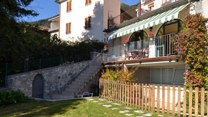 Un bâtiment à deux étages avec un escalier en pierre menant à une terrasse en bois.