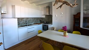 A modern kitchen with white cabinets, a wooden countertop, and a dining area with a white table and yellow chairs.
