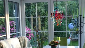 A conservatory with a glass table, green chairs, and a sofa with a blanket. - Only 250m to the beach - for 4 pers., 70sqm, large balcony. South-facing garden/terrace, conservatory (Schönberger Strand)