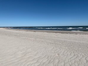 Une plage avec une vaste étendue de sable et l’océan en toile de fond.