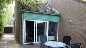 Eine Terrasse mit Tisch und Stühlen, eine Schiebetür und eine Ziegelwand.