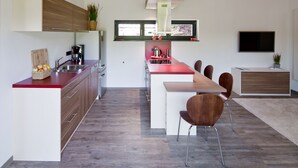 Une cuisine moderne dotée d’un îlot central, de meubles en bois et d’un coin repas avec des chaises.