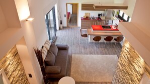 Une cuisine moderne avec un plan de travail rouge, un coin repas avec trois chaises et une grande fenêtre qui laisse entrer la lumière naturelle.