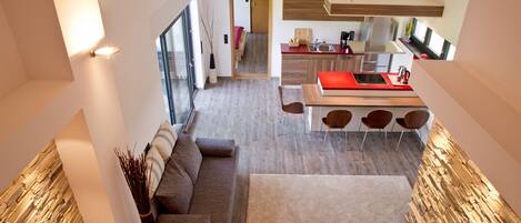 A modern kitchen with a red countertop, a dining area with three chairs, and a large window providing natural light.