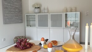 Esmorzar amb croissants, raïms, ous i suc d'aranja sobre una cuina moderna.