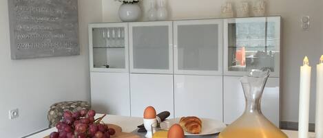 A breakfast setup with croissants, grapes, eggs, and orange juice on a modern kitchen counter.