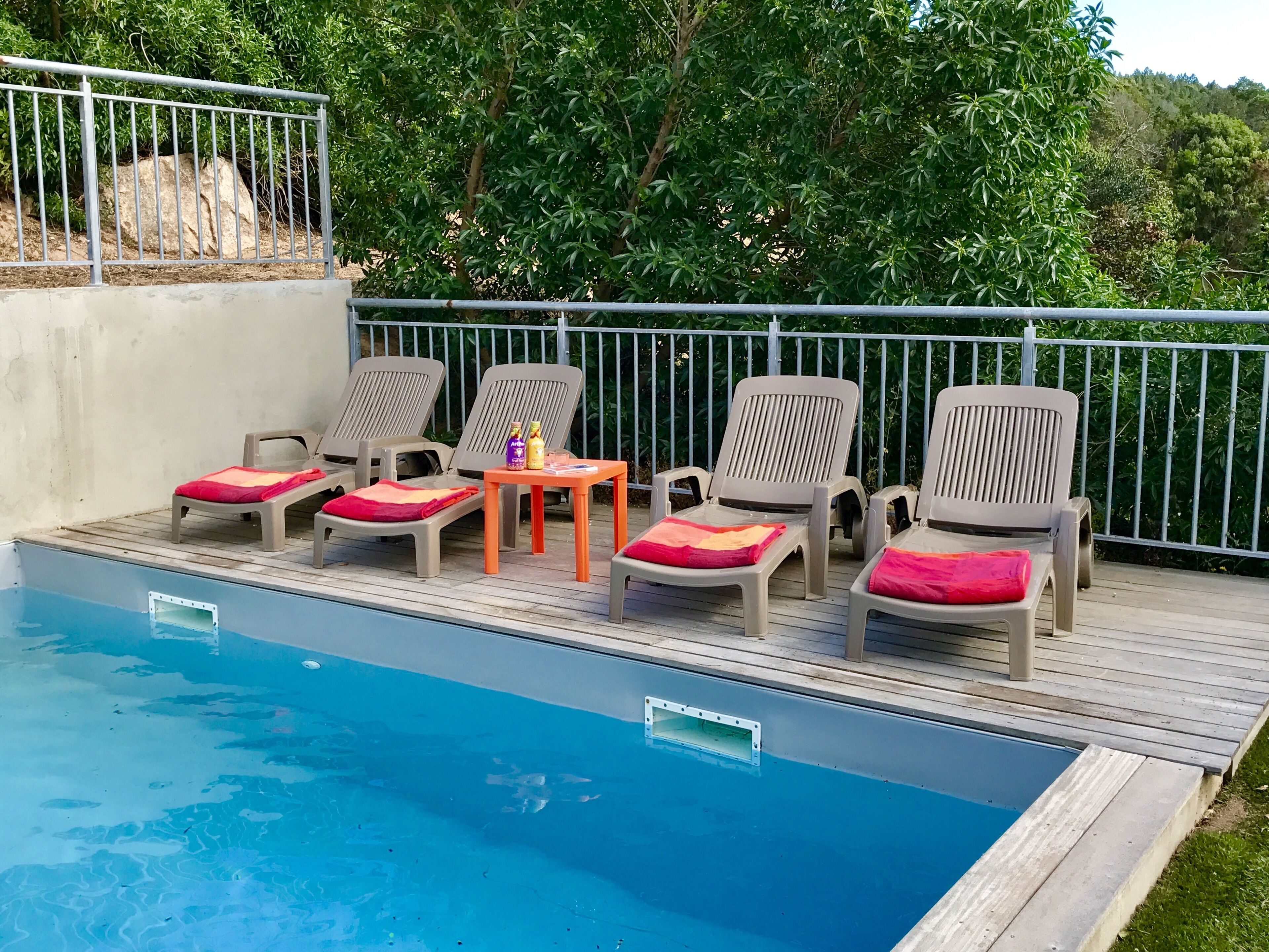 A poolside area with lounge chairs and a small table with bottles.