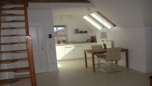 Una cocina moderna con comedor, que incluye una mesa y sillas de madera, tragaluz y vistas al exterior.