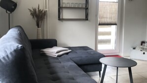 Una sala de estar moderna con un sofá gris, una mesita redonda y una estantería.