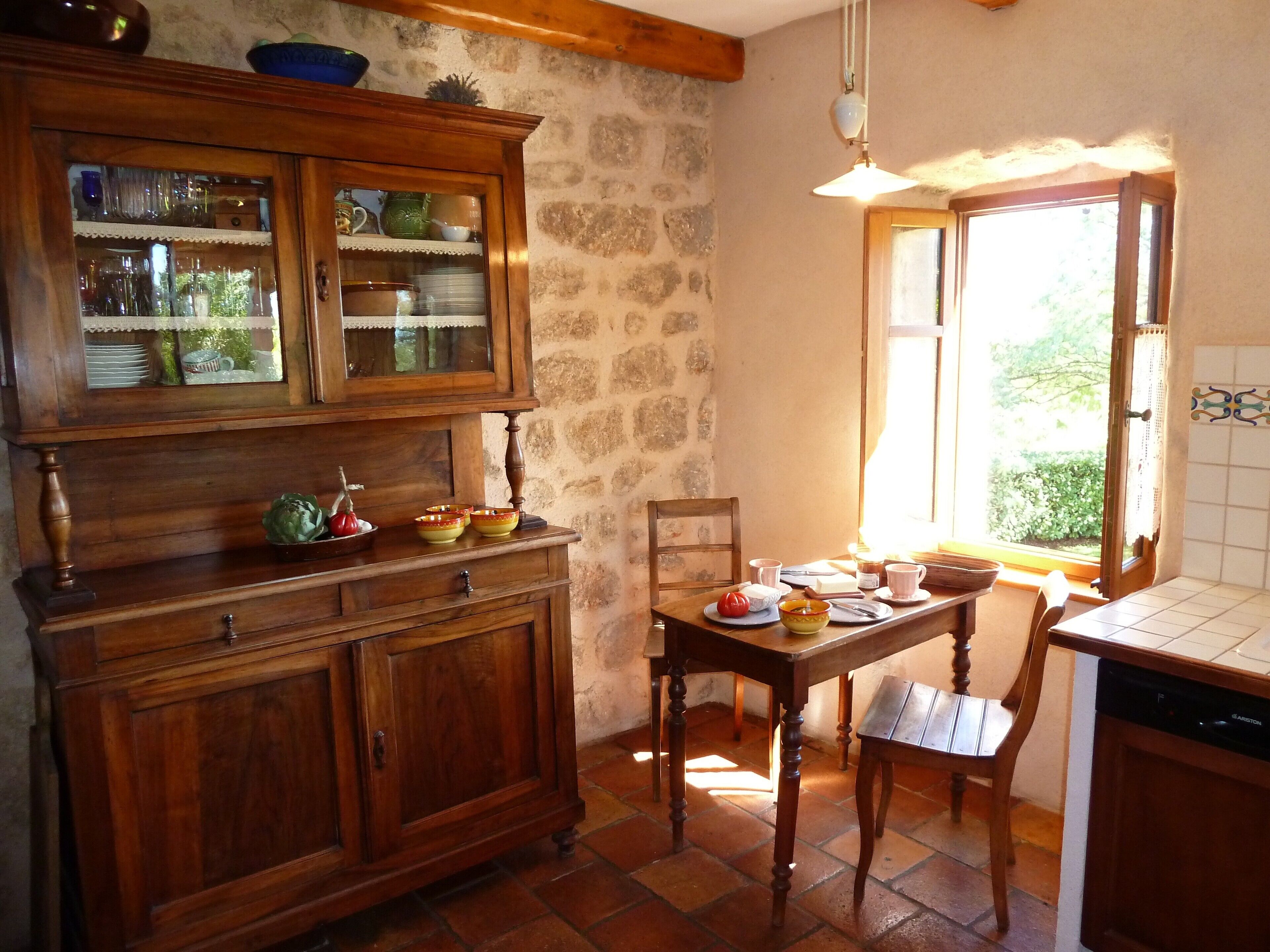 Una cocina rústica con un armario de madera, una mesa de comedor, sillas y una ventana con vistas a la vegetación.