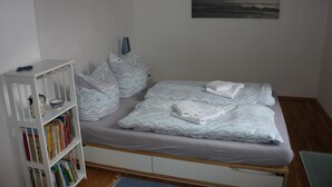 Une chambre à coucher avec un lit, des oreillers, une bibliothèque et un tableau accroché au mur.