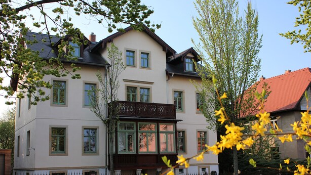 Un bâtiment à deux étages doté d’un balcon, d’une enseigne et d’un toit recouvert de tuiles rouges.