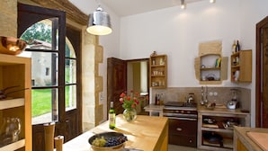 Una cocina con encimera de madera, un bol de fruta, un florero con flores y varios electrodomésticos.