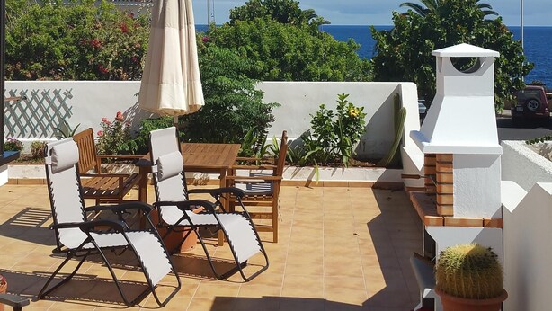 A patio with a table and chairs, a grill, and a view of the ocean. - A stone's throw from the Atlantic Ocean - 50 meters to the sea (Los Silos)