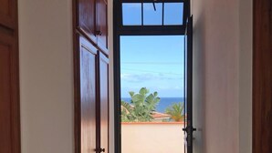A hallway leading to a balcony with a view of the ocean and tropical plants. - A stone's throw from the Atlantic Ocean - 50 meters to the sea (Los Silos)