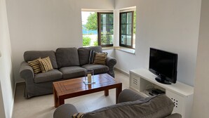A living room with a grey sofa, a wooden coffee table, and a TV on a white stand. - A stone's throw from the Atlantic Ocean - 50 meters to the sea (Los Silos)