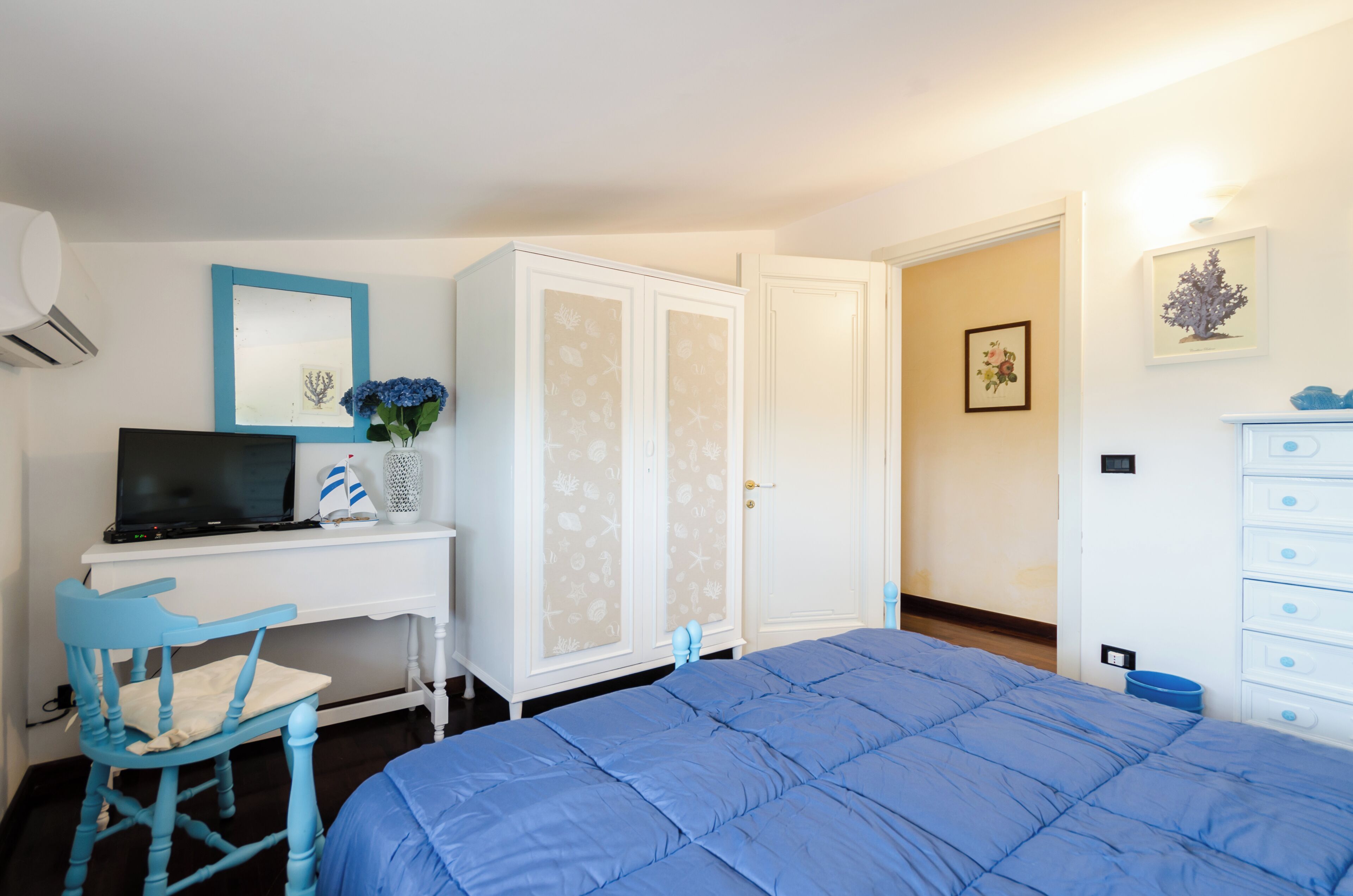 Een slaapkamer met een bed, bureau met een computer, een stoel, kledingkasten en een dressoir.