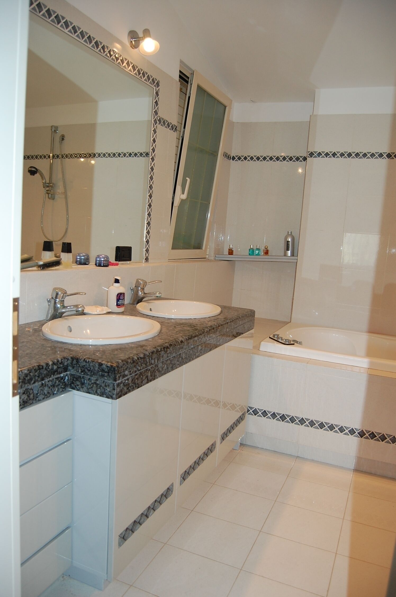 A bathroom with two sinks, a bathtub, and a large mirror.