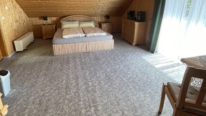 A cozy attic bedroom with a large bed, wooden walls, a ceiling light, and a view of the outdoors. - Detached vacation home with sauna and whirlpool for individual use (Thüringen)