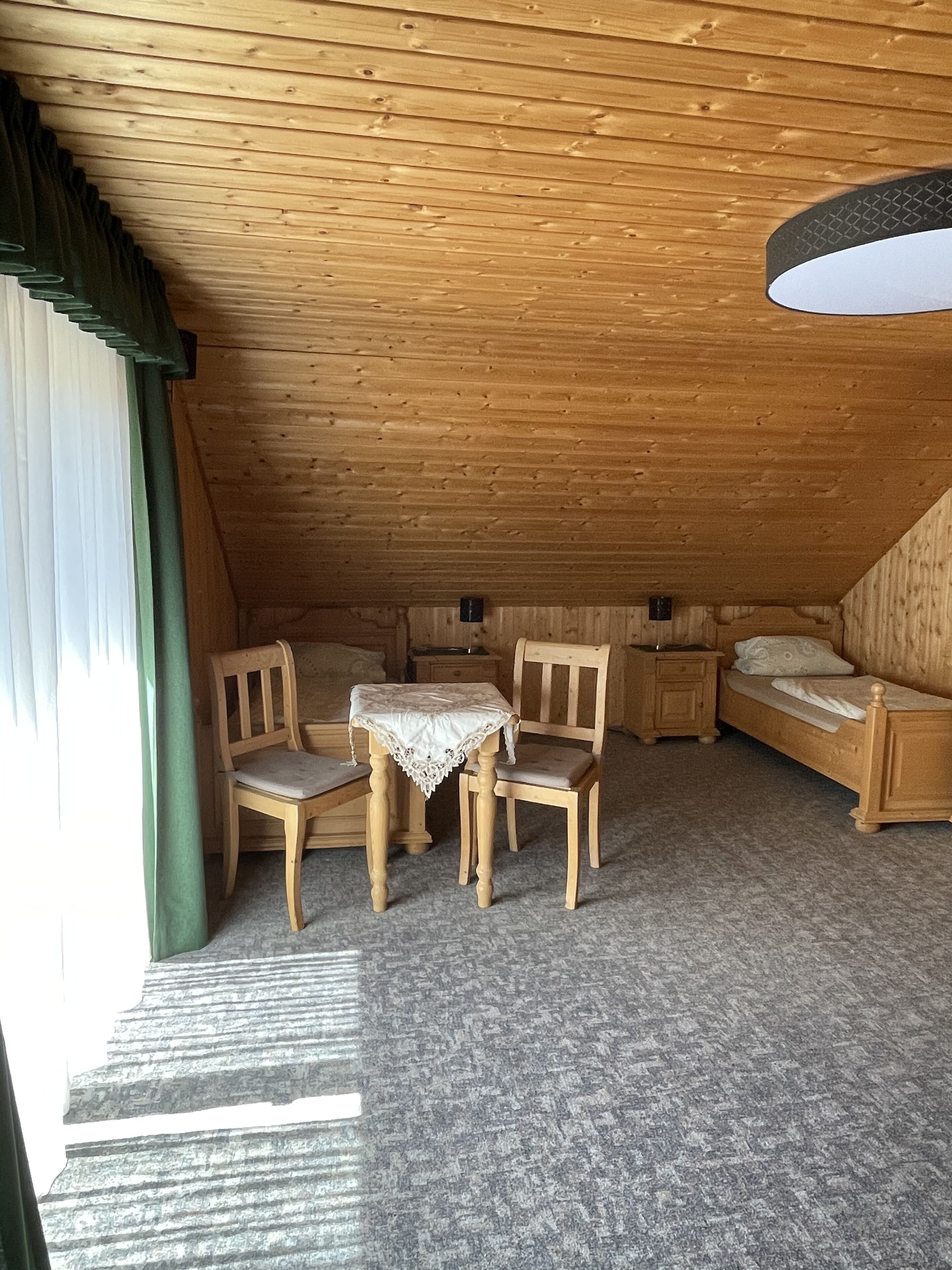 Un dormitorio acogedor en el ático, con techo inclinado, muebles de madera y una pequeña mesa.