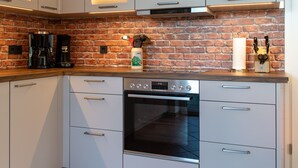 Eine Küche mit weißen Schränken, einer Ziegelrückwand, einem Backofen von Bosch und einer Kaffeemaschine.