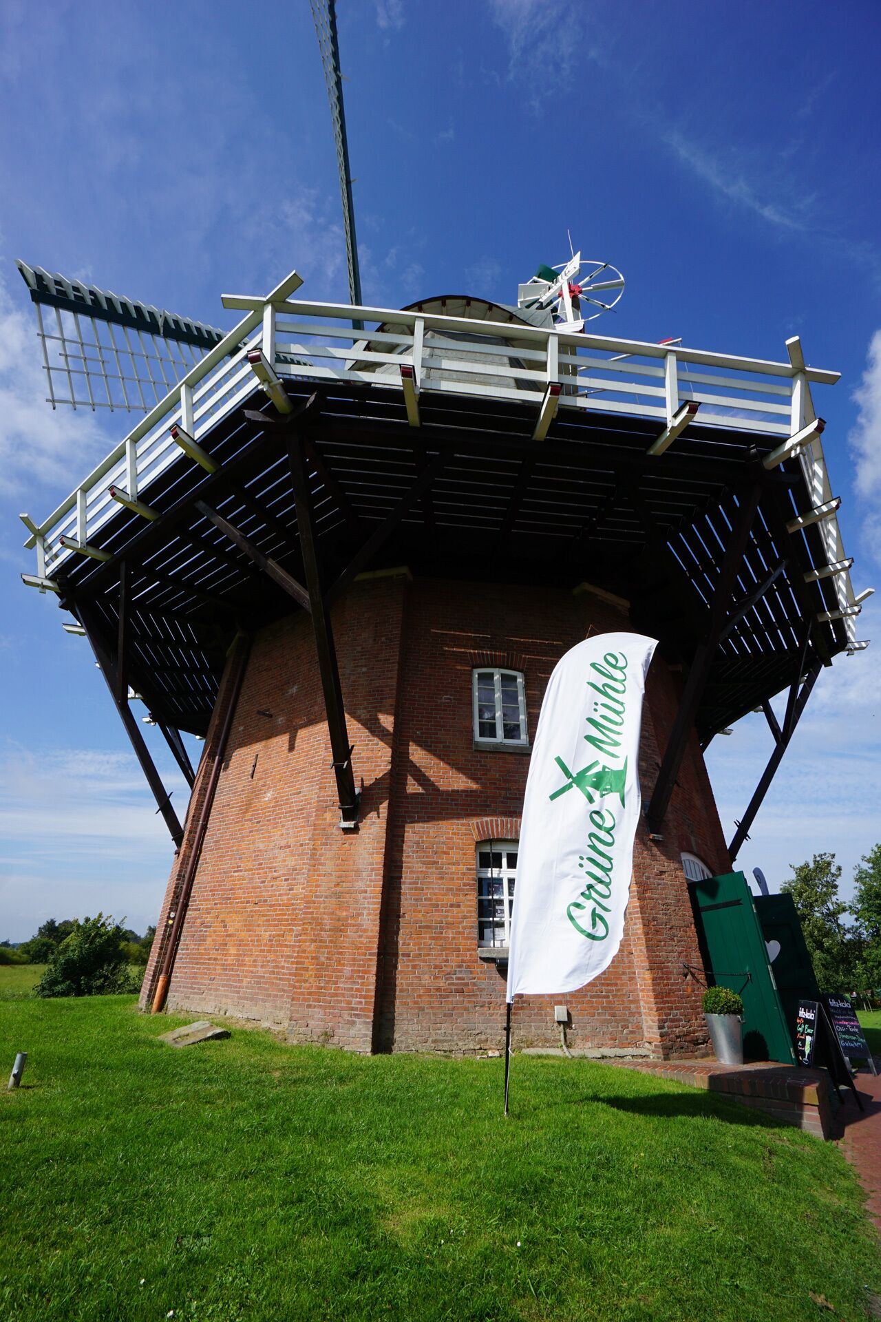 Eine traditionelle Windmühle mit einem weißen Banner, auf dem "Grüne Mühle" steht, und einer grünen Tür.