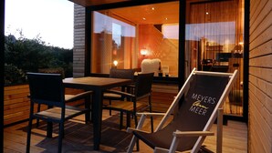 A modern outdoor seating area with a wooden deck, a table, and chairs. - Rent a bungalow, 300 mtr to the beach, private ground, 4 pers. (Ostseeferiendorf Zierow)
